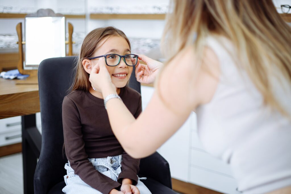 Opticien past een bril bij een lachend meisje